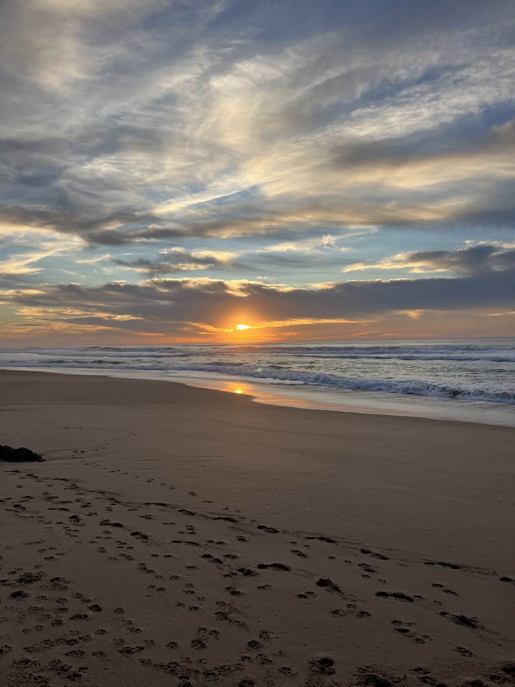 Sunset over the Atlantic with footprints in the sand